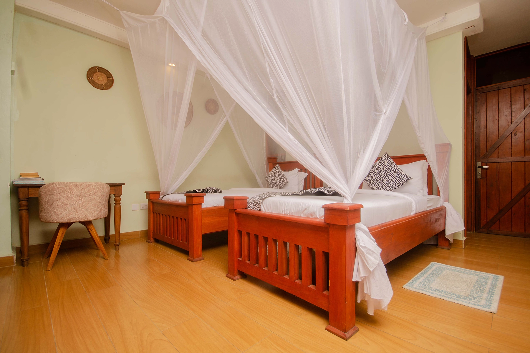 Twin bedroom at Amani Safari Lodge Tanzania with mosquito net canopies over red mahogany beds and African basket wall dÃ©cor