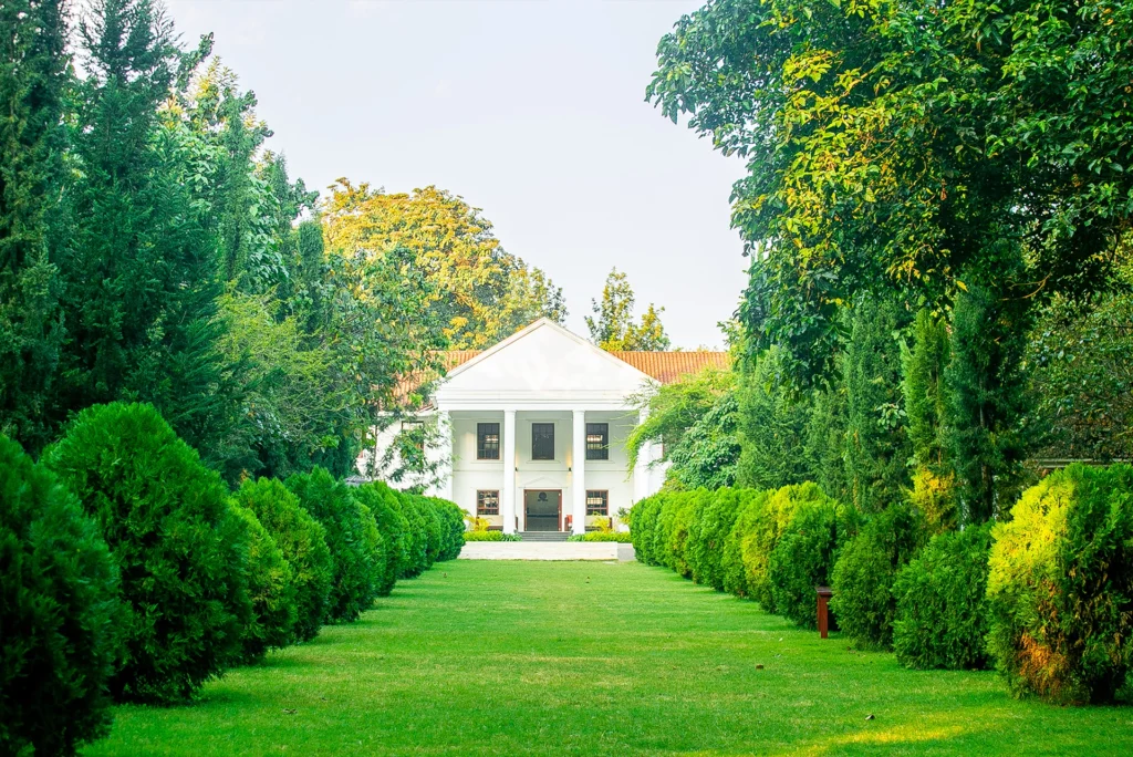 Colonial-style facade of Amani Safari Lodge in Tanzania with white columns and lush gardens