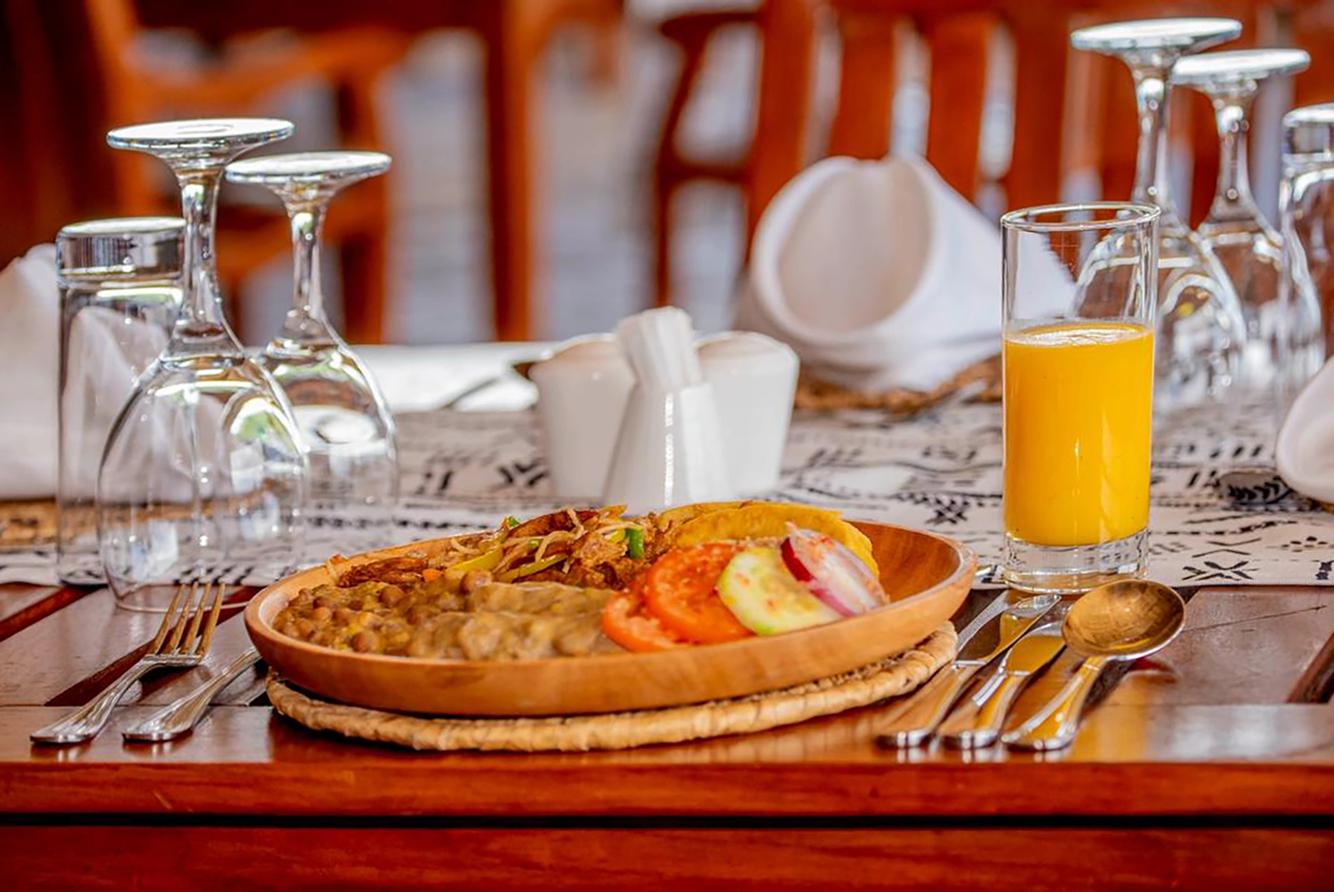 Traditional Tanzanian cuisine plated at Olduvai Museum Restaurant, served with fresh juice on a safari dining table