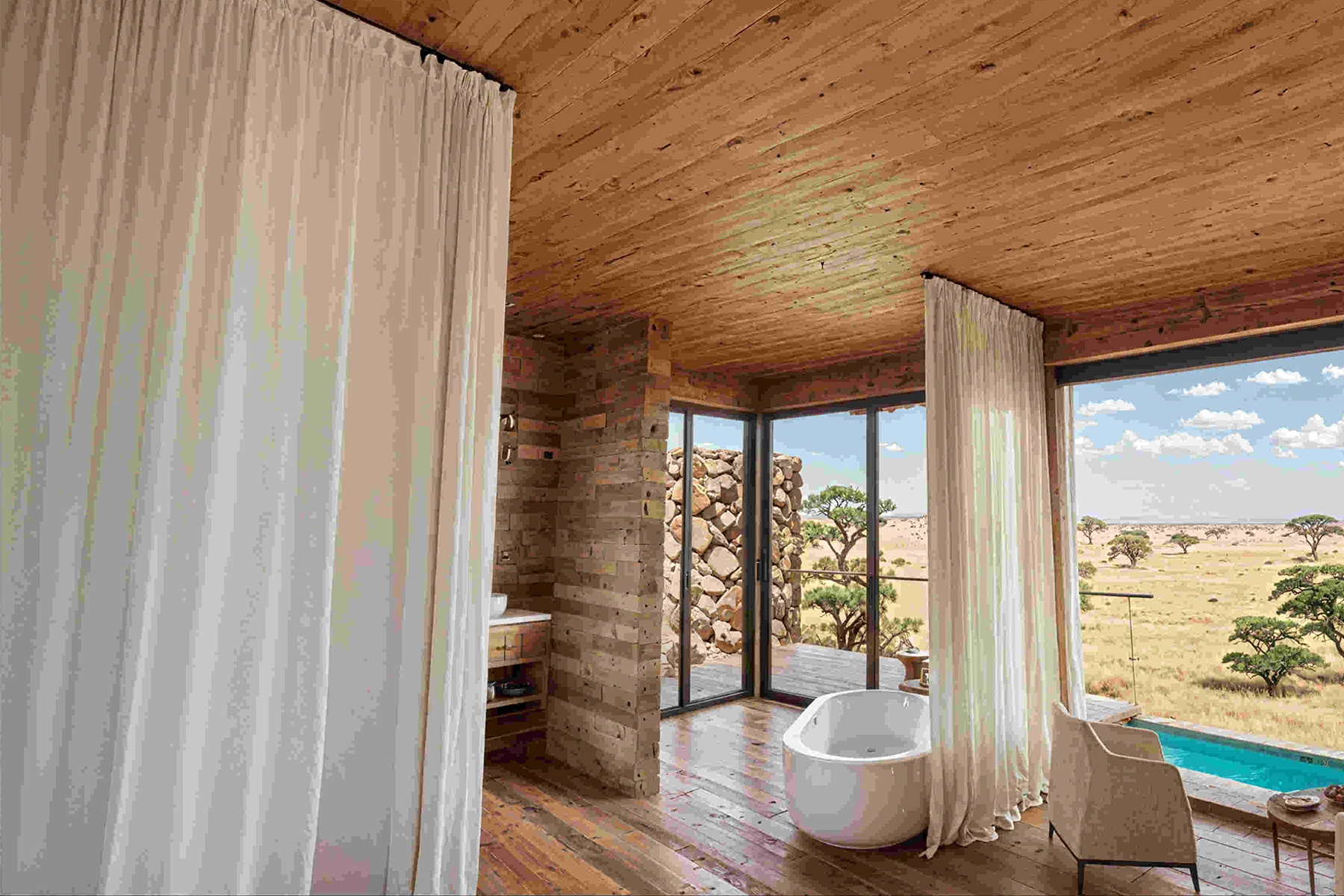 Architectural render of a villa en-suite bathroom at The Bomas by Amani Collection Lobo Serengeti, featuring a freestanding soaking tub, stone walls, timber ceiling, sheer white curtains, and floor-to-ceiling glass doors opening to a private pool with Serengeti views